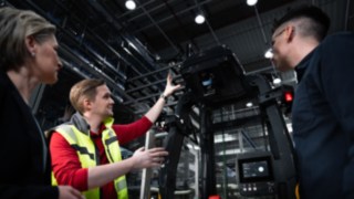 Tre personer står framför en automatiserad truck från Linde MH.