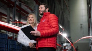 myLinde är flexibelt och kan anpassas till utmaningarna som just ert företag står inför. En man från Linde MH i röd jacka och en kvinna i vit skjorta står i en lagerlokal och tittar i fjärran.