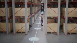 Animation av en kvinnlig medarbetare i varselväst i ett smalgångslager, samt säkerhetszonerna för persondetektering