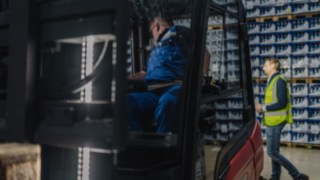 En fotgängare i varselväst korsar lagret bakom en truck. En fotgängare i varselväst korsar lagret bakom en truck.