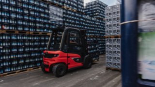Den elektriska motviktstrucken Linde X30 transporterar drickabackar genom en smal gång i ett utomhuslager.