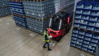 Lindes elektriska motviktstruck X30 backar ut från en gång. I bakgrunden står en fotgängare.