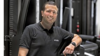 Tibor Sevenheck från Future Warehouse Team på Arvato. Tibor Sevenheck lutar sig mot en smalgångstruck och ler mot kameran.