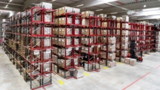 Ett smalgångslager med tre smalgångstruckar från Linde framför hyllgångarna.
