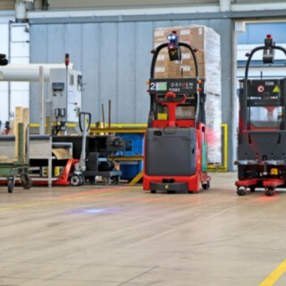Två automatiserade ledstaplare av typen L-MATIC transporterar gods mellan förpackningslinjen och transitlagret.