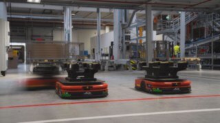 Tre autonoma mobila robotar (AMR) från Linde MH färdas genom lagret