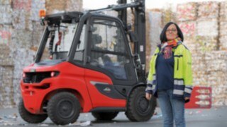 Förarna står i centrum för hela Linde-truckfilosofin. En kvinna står framför en truck på ett fabriksområde