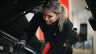 Servicetekniker Hanna mekar på en truck i en verkstad.